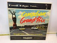 Front cover of the vinyl record titled 'Canadian Grand Prix' showing racing cars and trophy statue, indicating the event and commentators.