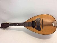 Front view of the antique mandolin showing the sound hole, pickguard, bridge, and fretboard with inlays