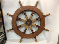Front view of the wooden ship's wheel showing all eight handles and the circular wooden structure.