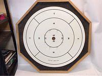 Octagonal crokinole playing surface showing concentric rings and central scoring area with pins.