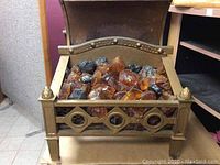 Front view of ornate metal electric fireplace showing amber glass pieces and coal embers inside metal grate.