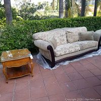 Photo showing fabric sofa with floral cushions and Stanley wood side table with glass top on outdoor patio