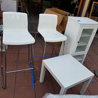 Full view of 2 white Ikea barstools, white square table, and white cabinet showing the overall condition and size relation.