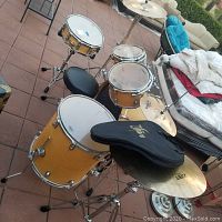 Overall view of drum set on patio including drums, stool and cymbal stands