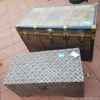Front and top perspective of wood chest with carved geometrical floral pattern, and metal clad chest with riveted metal bands and brass tone lock hardware.