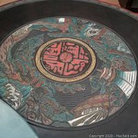 Close-up of the table's center carved decoration under glass showing Asian style motifs and symbols.