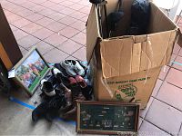 Photo of golf clubs, golf shoes, boots piled next to two framed golf-themed wall art pieces on the floor.