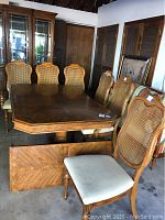 Wood dining table with leaf and six wood and wicker-back chairs with fabric seats