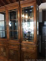 Overall view of wooden hutch showcasing glass cabinet doors, shelves inside, and three lower drawers and cabinets.