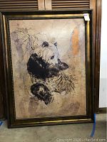 Full view of the large panda painting in a decorative dark brown frame leaning against a wall, shows overall condition and large size.