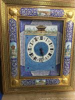 Full view of the framed wall clock showing intricate border with Middle Eastern architectural miniatures and blue patterned background around the clock face with Roman numerals.