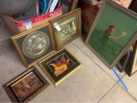 Five framed wall art pieces arranged on the floor showing variety of styles and sizes