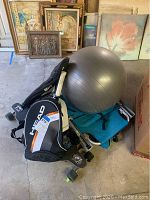 Black and white Head tennis racket bag, gray yoga ball, foldable blue beach chair and skateboard grouped on floor