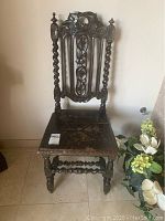 Front view showing detailed carvings on backrest and seat, twisted pillar legs, and vintage wear marks.