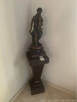 Full view of metal sculpture on wooden pedestal