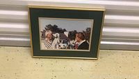 Photo of framed color photograph showing Greg Norman and Jack Nicklaus at the Masters Tournament in Augusta. Green matting and gold-trimmed frame visible.
