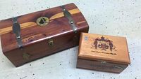 Photo of two wooden cigar boxes; larger Pennsylvania box with metal clasps and emblem, smaller Dominican Republic box with printed crest and text.