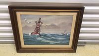 Front view of framed seascape painting showing buoy, seagulls, and ship in a stormy sea environment.