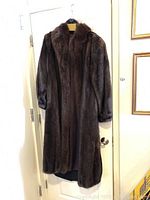 Full front view of dark brown mink coat hanging against door