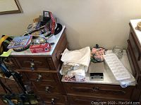 Wide shot of the kitchen items including towels, aprons, ice cube trays, digital kitchen scale, measuring cups, and other small kitchen items arranged on two wooden dressers.