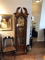 Full front view of wooden longcase grandfather clock with swan neck pediment, glass door and base