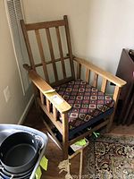 Front and side view of the wooden chair with patterned cushion, showing overall style and condition