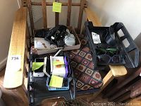 Wide view of lot items arranged on a wooden chair including cables, phones, charger, sunglasses.