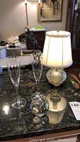 Overall view showing two Tiffany champagne flutes, the Tiffany & Co apple paperweight, and the Waterford crystal lamp on a countertop.