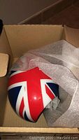 Union Jack painted MINI side mirror cap packed in protective foam inside open cardboard box.