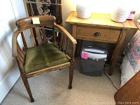 Photo showing side table next to oak armchair with green cushion, side table with drawer and natural wood finish.