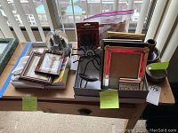 Wide view of all items on table including picture frames stacked, snow globe, wall brackets, and two stone pieces with labels