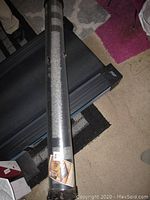 Area rug rolled and plastic wrapped lying on floor showing full packaging length.