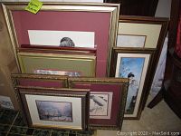 Framed wall art stack showing edge of multiple frames with maroon matting and gold trim