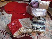 Photo showing three red circular IKEA rugs, one rectangular red rug, four throw pillows, and three throws arranged together.