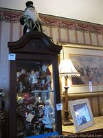 Various Santa figurines displayed inside glass cabinet along with other decorations