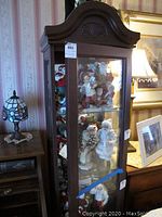 Front view of the wood curio cabinet filled with collectible figurines inside for display purposes only.