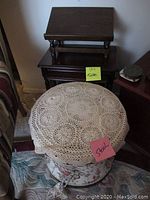 Photo showing the floral upholstered stool with lace cover and one nesting table behind it.