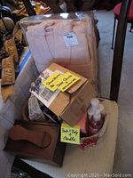 Shoe shine box, ladies robe in plastic box, slippers, basket with bath and body items and candle visible.