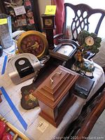 Photo showing five clocks and radios including wooden mantle clock, wall clock, Emerson silver alarm clock radio, and GPX alarm clock with radio and CD player