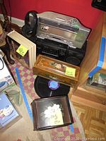 Sony radio cassette-corder with headphones, Jensen CD player beneath, wooden box of cut cassette tapes, box of old CDs, and visible LP record on floor.