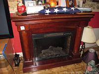Front view of Twin Star electric fireplace with wooden mantel and decorative items on mantel shelf.