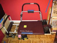 Pilates Performer exercise machine showing padded seat with handle frame and foot adjustment components.