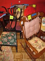Photo showing wood rocking chair with pink gingham and floral cushions, pair of harp back dining chairs (one with green floral cushion), and part of US flag seat chair.