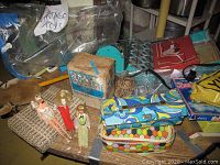 Overview of vintage toys, dolls, boxed sets, and doll cases packed together on the floor