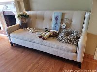 Front view of cream cloth sofa showing button-tufted backrest, three-seat cushion, and some items placed on seat