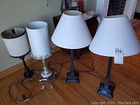 Four table lamps of varying styles shown together, cords visible, standing on wooden floor