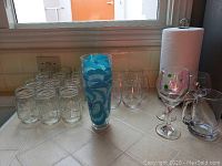 Various sizes of clear canning jars, tall blue and white pattern drinking glasses, stemware with colorful polka dots, and clear glass drinking glasses on kitchen counter.