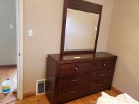 Full dresser with mirror mounted on top against wall, showing wood finish and overall size