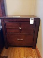 Front view of the wooden nightstand showing two drawers with different handles, wood finish and square shape.
