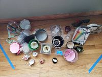 Top-down view of assorted decorative items including votive holders, small containers, and clock on wood floor.